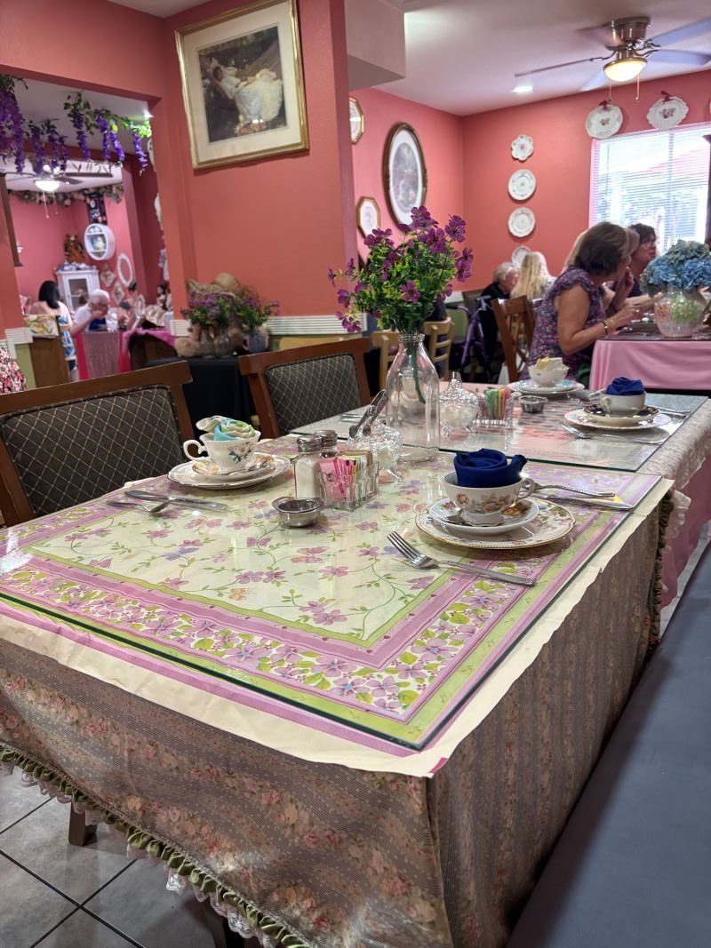 Table setting at The Pink Door Tea House featuring pink tea sets, patterned tablecloths, and vintage utensils.