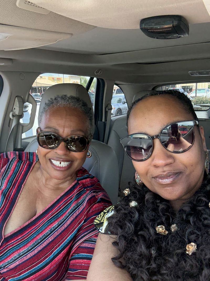 Two women sitting in a car, smiling on their way to The Pink Door Tea House for a Mother’s Day outing.